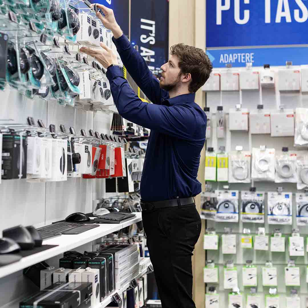 Employee from Elgiganten in Frederiksberg stocking items on the shelves.